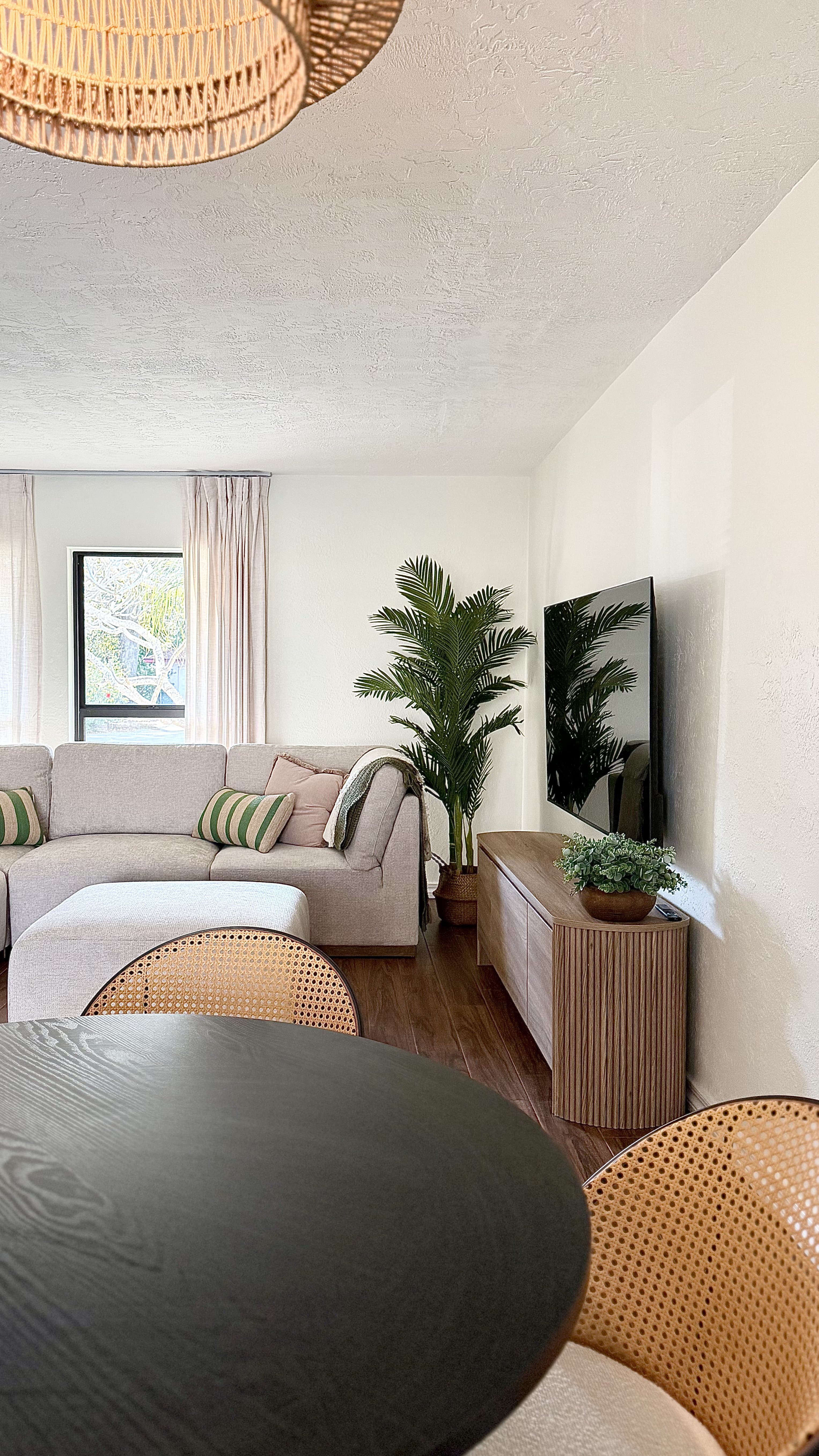 Living room corner with linen sofa and rattan pendant